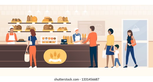 People shopping in the bakery and shop assistants working and selling fresh bread to the customers