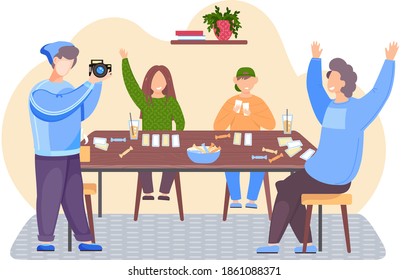 People are sitting at a table and playing a board game. The guy is holding camera and adjusting the lens. Family is having fun and communicating together. Photographer during photo shooting at home