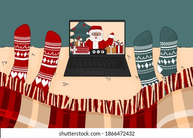 People are watching laptop screen, it is video call with Santa Claus in Christmas time. They are on the bed with knitted red and blue socks