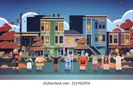 people wearing different monsters costumes walking in town tricks and treat happy halloween party celebration concept city street buildings exterior cityscape background full length horizontal