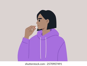 A person in a cozy purple hoodie thoughtfully prepares to take a pill, embracing a moment of self-care and reflection on health and well-being