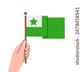 Person holding green esperanto flag in hand