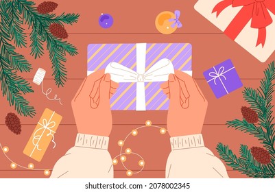 A person prepares a Christmas present, ties a ribbon bow on a box