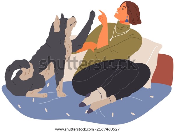 Pet owner plays with dog. Caring for animals, joint\
pastime with pets concept. Happy lady with puppy, domestic animal\
companion at home. Dog follows command, gives paw to woman. Girl\
training doggy