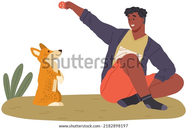 Pet owner plays with dog. Caring for animals, joint
pastime with pets concept. Happy guy with puppy, domestic animal
companion at home. Male character training doggy. Man spends time
with corgi dog
