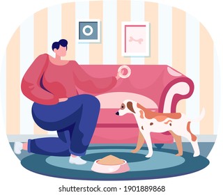 Pet owner woman playing with dog at home, takes care of him, funny girl training puppy, gives him donut. Female is having leisure spend time with domestic animal cute doggy, feeding dog food from bowl