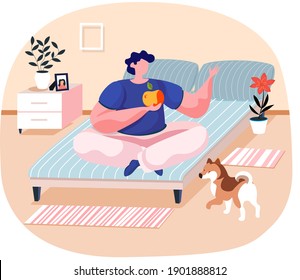 Pet owner young man sitting on bed in bedroom on lotus position holding an apple with cute dog. Male character is having leisure spend time with domestic animal funny doggy. Guy meditates with dog