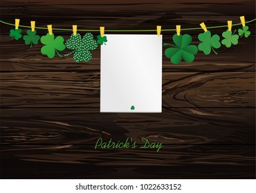 Petals of clover with a picture hanging with paper blank on a rope with clothespins. St.Patrick 's Day. Vector illustration. Greeting card with empty space for text or advertising. On a wooden back