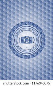 photo camera icon inside blue emblem or badge with abstract geometric pattern background.