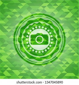 photo camera icon inside green emblem with mosaic ecological style background