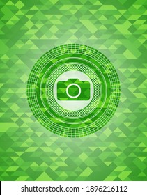 photo camera icon inside green emblem with mosaic ecological style background. 
