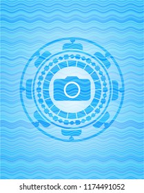 photo camera icon inside light blue water badge.