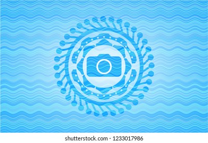 photo camera icon inside light blue water badge.
