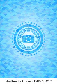 photo camera icon inside light blue emblem with triangle mosaic background