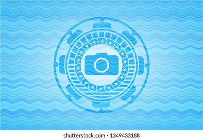 photo camera icon inside light blue water style emblem.