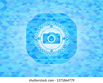 photo camera icon inside light blue emblem with triangle mosaic background