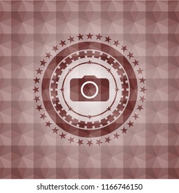 photo camera icon inside red seamless emblem or badge with abstract geometric pattern background.