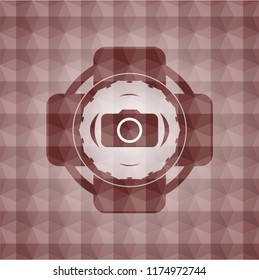 photo camera icon inside red seamless emblem or badge with abstract geometric pattern background.