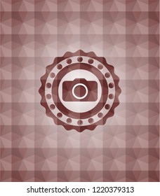 photo camera icon inside red seamless emblem or badge with abstract geometric pattern background.