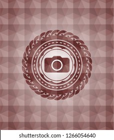 photo camera icon inside red seamless emblem with geometric pattern background.
