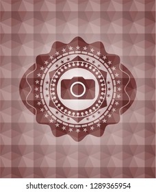 photo camera icon inside red seamless emblem or badge with abstract geometric polygonal pattern background.