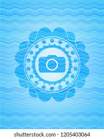 photo camera icon inside sky blue water emblem.
