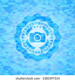 photo camera icon inside sky blue emblem with mosaic ecological style background