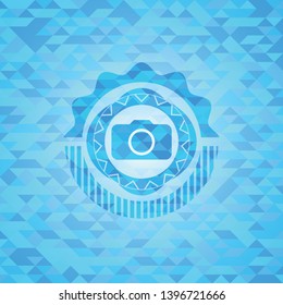 photo camera icon inside sky blue emblem with triangle mosaic background