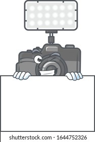 Photo camera with lighting cartoon character with funny face hides behind a board
