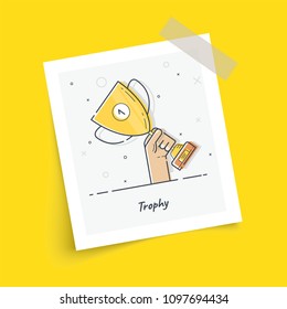 Photo frame on sticky tape with gold cup in hands. Hand holding winner's trophy award. Trendy flat vector on yellow background. Vector Illustration. 