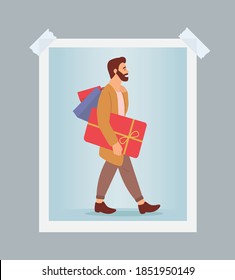 Photo of a serious man with gift boxes in his hands. Young handsome fashion shopper guy isolated on blue background. Male character in store is buying christmas presents and posing with purchases