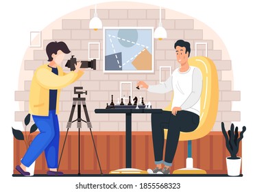 Photographer takes photos of a man playing chess in cozy living room atmosphere in the evening. Male character holds a pawn in hand and makes a move, hobby, competition, logic game on the weekend