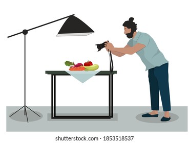 The photographer takes a picture of a still-life composition. A man with a camera takes photos of vegetables on a table under a spotlight. Vector illustration.