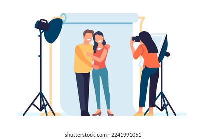 Photographer takes pictures of posing happy couple. Photo studio with professional lighting. Photoshoot Love story. Cameraman making snapshots. Photography shooting