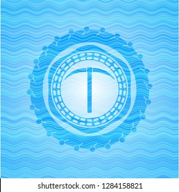 pickaxe icon inside water wave concept badge.