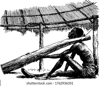 The picture depicts the slave sitting on the ground with the slave fork, a forked branch of a tree, four or five feet long, out in front of him. He is in an enclosure with a thatched roof, vintage.