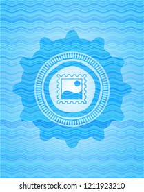 picture icon inside light blue water wave style emblem.