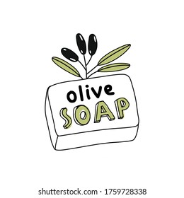 A piece of handmade olive soap with a branch of black olives.