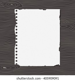 Piece of torn white notebook grainy paper is stuck on dark wooden wall or desk