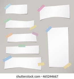 Pieces of cut white note paper are stuck with striped sticky tape on gray background