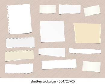 Pieces of different size ripped note, notebook, copybook paper stuck brown background