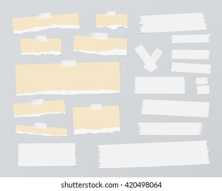 Pieces of ripped blank note paper, sticky, adhesive tapes are stuck on gray wall