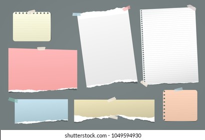 Pieces of torn colorful and white, lined note, notebook paper strips stuck on dark background