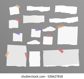 Pieces of white and beige torn note, notebook paper sheets stuck on grey background