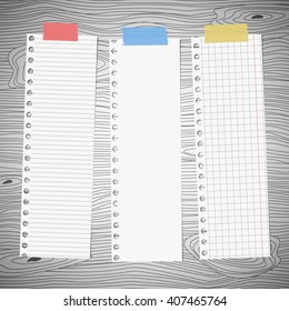 Pieces of white squared, lined note paper is stuck on gray wooden wall or desk