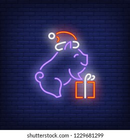 Piglet with gift neon sign. Glowing piggy in santa cap with gift on dark blue brick background. Can be used for christmas, new year, advertisement