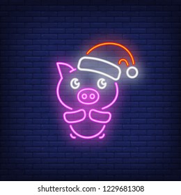 Piglet in santa cap neon sign. Glowing piggy in red hat on dark blue brick background. Can be used for christmas, new year, advertisement