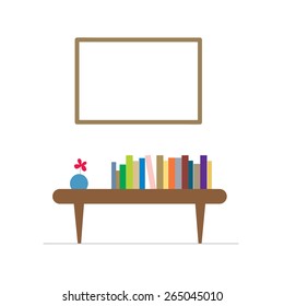 pile of books and a vase on a table with a large frame on the wall