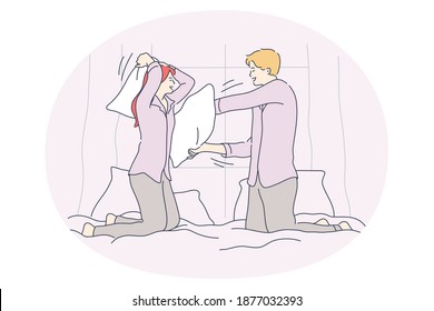 Pillow fighting and battle concept. Young happy couple fighting with pillows in bed and having fun during funny cheerful jaunt pastime together at home 