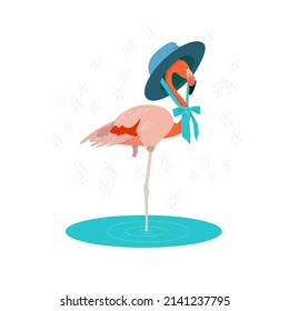 A pink coquettish flamingo in a blue hat with a bow stands in a lake